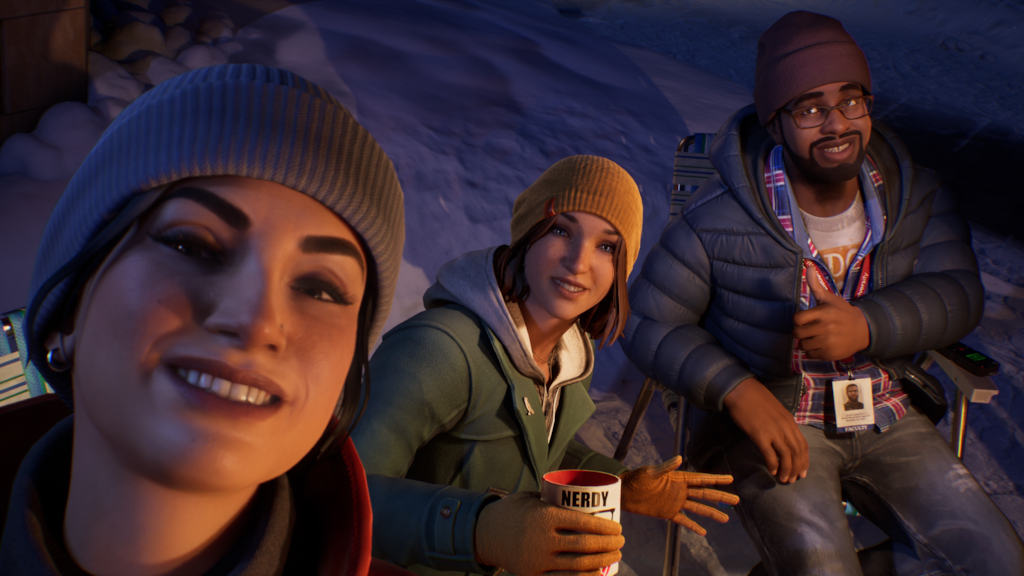 Auto-generated description: Three people wearing winter clothing are outdoors, with one taking a selfie while the others smile and hold warm drinks.